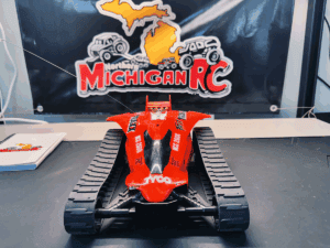 Front view of restored red Tyco Fast Traxx RC car with Northern Michigan RC logo in background